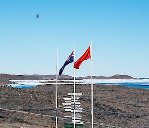 The Australian and Chinese flags are flying from the flagpole. Above them a helicopter is visible, flying into station.