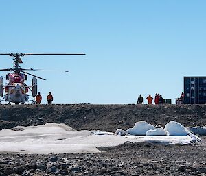 The Kamov helicopter is on the helipad, people are walking around the machine.