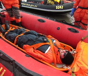 Jock is strapped into a stretcher, which is lying in the Zodiac. Done as part of our safety training.