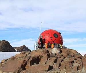 A red fibreglass refuge, referred to as a melon due to its shape, located on rocks beside the icy Trajer Ridge.