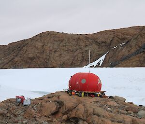 The red melon sits on the rocks. You can see the platform on which is sits.