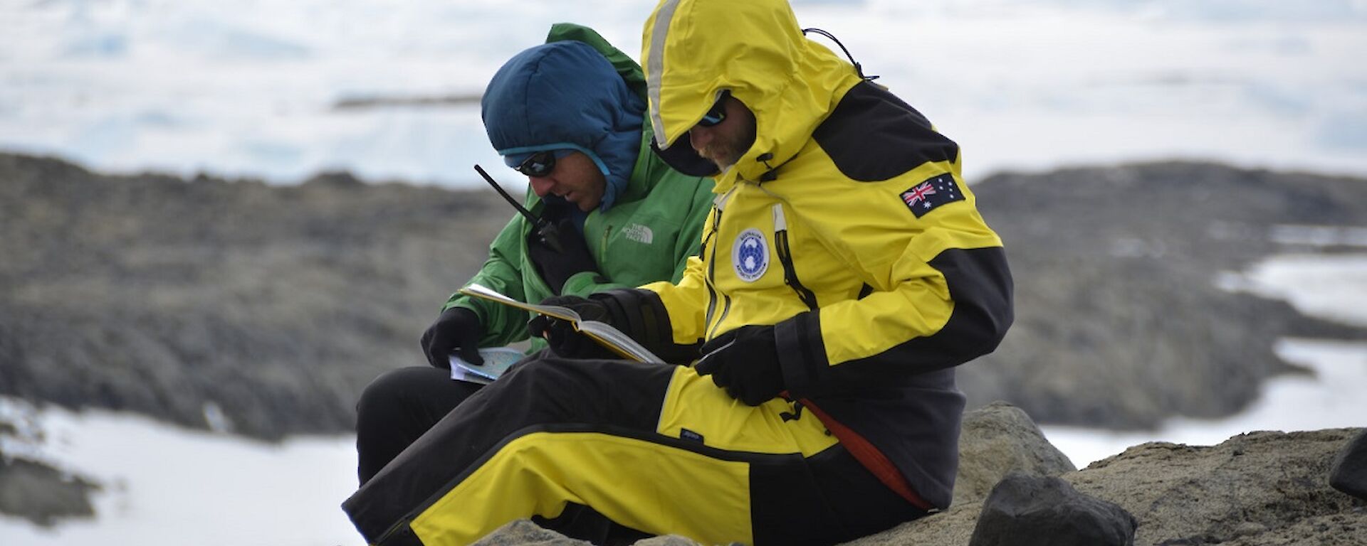 Nick and Marcello are sitting on the ground, studying rocks.