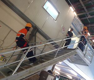 Bryce is roped up and descending backwards down stairs in the Greenstore, practising abseiling techniques.