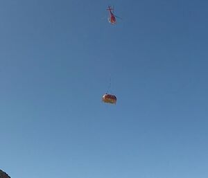 A helicopter slinging the melon over the Trajer Ice Ridge and surrounding mountains, back to station.