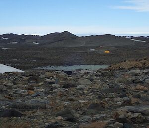 A view of a tent off in the distance, over very rock ground. This is where the cable will be dragged out to.