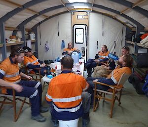 A group of people sitting on chairs in a tent.