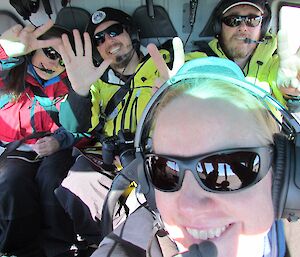 Four excited expeditioners sitting inside a helicopter at the start of their visit to see the neighbouring stations.