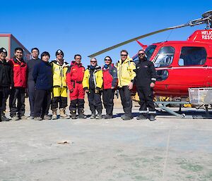 Australian and Chinese expeditioners stand together for a photo beside the Australian helicopter.