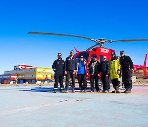 Australian and Russian expeditioners stand together for a photo in front of the Australian helicopter.