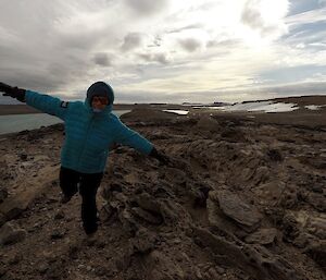 An expeditioner with her arms out, enjoying the wind coming off the plateau, out in the hills.