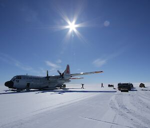 People are around the back of the plane, moving cargo between the plane and the waiting vehicles