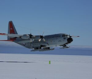 The hercules is taking off. It is a side on view where you can see the skis attached to the landing gear.
