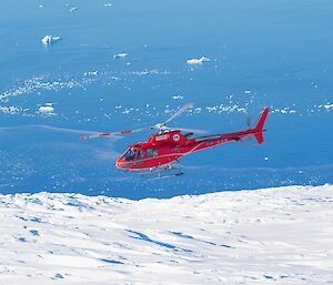 The red helicopter flies over a heavily crevassed glacier. Heading home after a day of work out in the field.