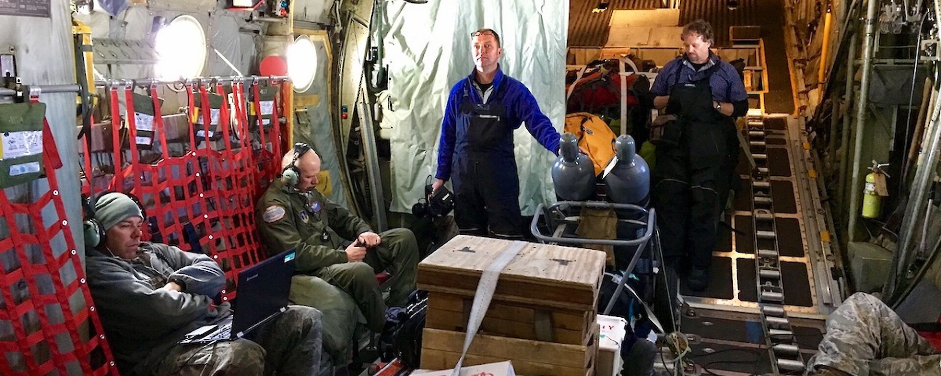 Military personnel, are standing inside the Hercules as it travels to Antarctica.