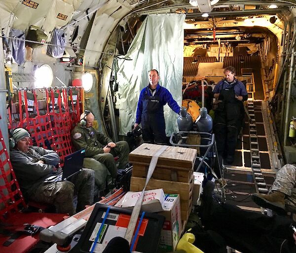 Military personnel, are standing inside the Hercules as it travels to Antarctica.