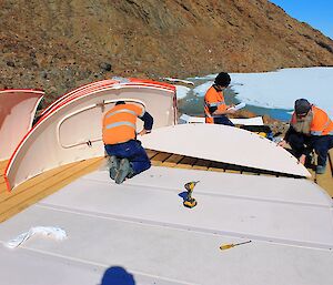 Two people are fitting floor panels for the new hut together. Rhys is reading the instructions.