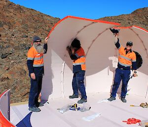 Ed and Vas are holding up the side panels of the melon in place while Rhys fixes them together.