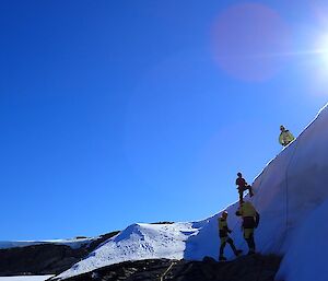 Four people are at various stages down the steep ice face of Trajer Ridge.