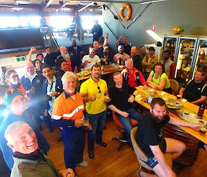 The bar is full of happy people watching the cricket on a big screen.