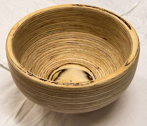 A bowl carved from layers of laminated plywood. It looks stripey as a result of the wood used.