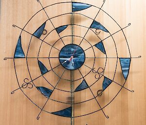 A metalwork clock, shaped like a spider’s web, with a swinging spider on the pendulum.