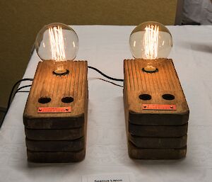 Two lamps, made from stacks of wooden rungs from a ship’s ladder, with bulbs with architectural filaments.