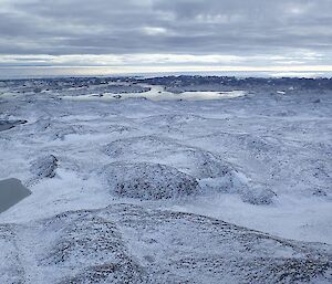 View from the helicopter looking over snow covered hills.