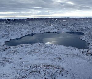 Aerial view of Deep Lake, looking dark and beautiful amongst the snow covered hills.