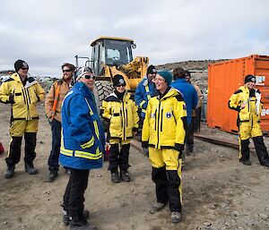 Kerryn and Sue are standing chatting. Other expeditioners are seen in the background. Everyone is waiting for the boat to arrive.