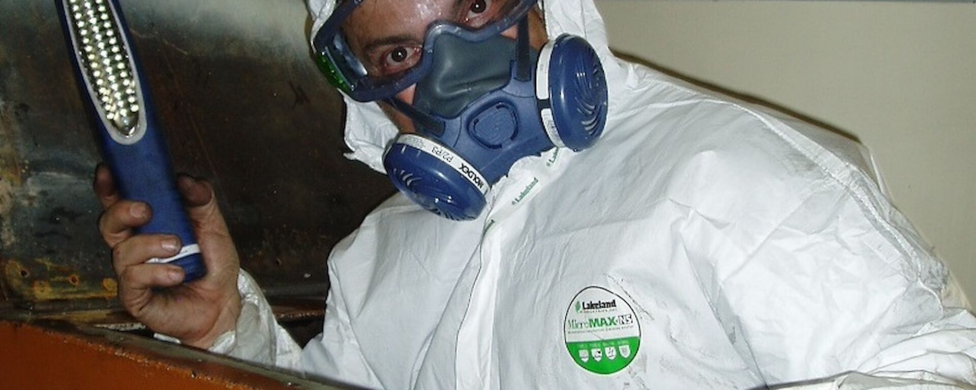 Tony is in the workshop, wearing a protective suit and a breathing mask