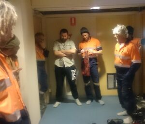 Six members of the trades team are standing around in the corridor of the SAM building working out a plan of attack prior to clean the area.