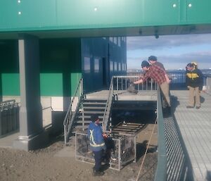 A group of expeditioners outside the living quarters building cleaning up.