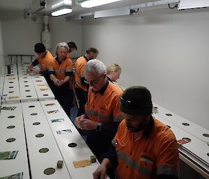 Richard, Sharky, Rhys, Fitzy, Kirsten, Rob and Tony are all planting seeds within the growing substrate that then get put into the growing channels.