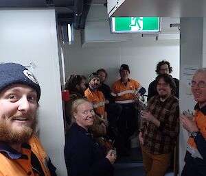 Nine people are standing around smiling and with a drink in hand, having just celebrated the official opening of the Hydroponics building.