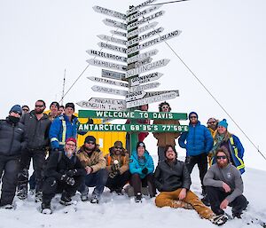 The team of 17 winterers arranged around the Davis sign post.