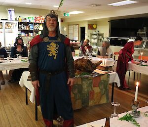 Richard is dressed as a king with a blue tunic, chain metal, a cape and crown. There is an insignia of a lion on his chest.