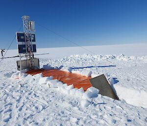 A large dug out section lies to one side of the AM06 equipment. There is a tarp and board over the hole to stop snow from entering between visits.