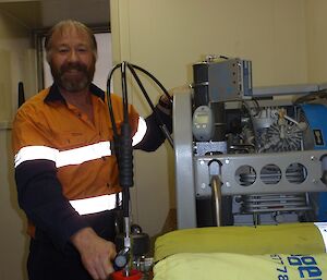 Fitzy is wearing high vis work clothes and is filling the air tanks which are used when fighting fires.