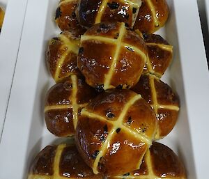 Freshly made hotcross buns, glistening with jam glaze and ready to eat.