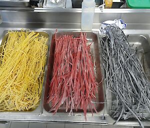 Freshly made spaghetti, beetroot fettucini and squid ink fettucini drying.