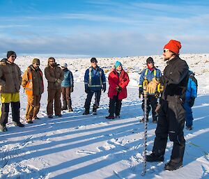 Lotter is holding a long drill bit, used for taking ice cores, in an effort to teach us about how to drill sea-ice to test for ice thickness and quality. The team are standing around in a circle listening to him.