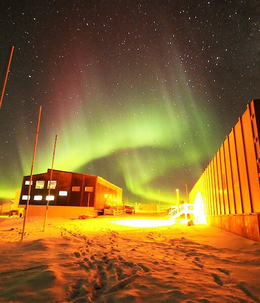 A green and magenta aurora is over the Living Quarters and Operations buildings.