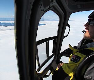 A photo of the helicopter cockpit as we're flying over glaciers, with Ralph’s smiling face. He’s enjoying the flight!