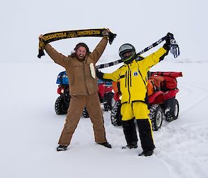 Bryce and Barry B2 show their support for their AFL teams by holding their footy scarfs over their heads.