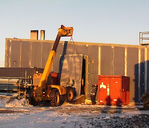 The crane is lifting the side panel away from the Main Power House building. This creates access to remove the old engine and deliver the new engine.