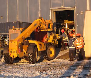 The JCB is carrying the new engine through the open side panel to get it inside the Main Power House.