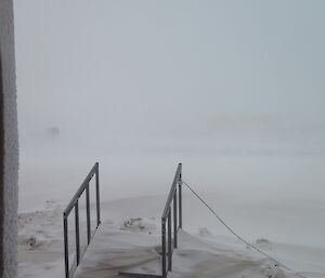 Some of the stairs handrail is seen but the rest is under thick snow.