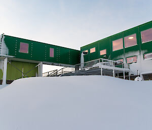 The green Living Quarters building with a dune of snow in front of it as a result of the blizzard.