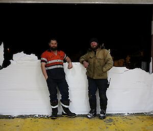 Marc and Jock leaning on the wall of snow, exposed after the workshop door was raised.