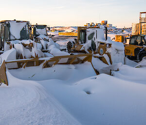 The bulldozers and other plant equipment also covered in snow.
